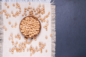 Bowl with organic dry chickpeas on an stone table pours into a bowl. copyspace