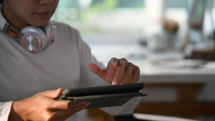 Cropped shot of creative designer male with headphone using tablet  while in modern office.