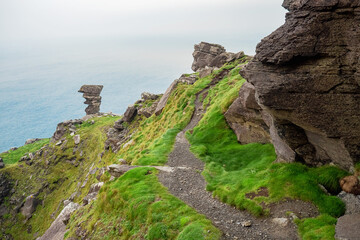Beautiful landscape scene view on rock formations and green grass patches. Cliff of Moher, county Clare. Ireland, Popular tourist destination. Warm day, Cloudy sky, Nobody.