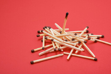 a pile of matches and one burnt match on a red background