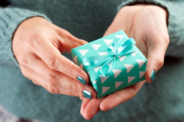 Close-up of female hand holding a present or gift for Christmas, New Year, Birthday, Valentine's day or any other celebration. 