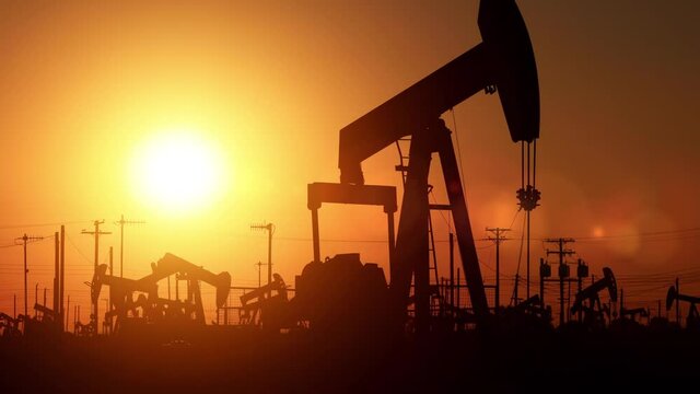 The sun rises behind oil pumps in California