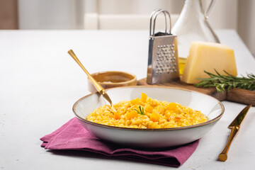 Lunch with pumpkin risotto on white table, hard cheese and olive oil on background. Selective focus. Copy space. Horizontal image.