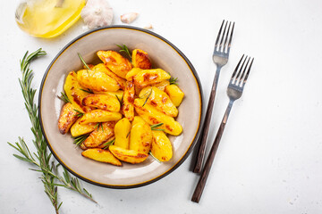 Oven roasted  potatoes with garlic, olive oil and rosemary. Vegan food. Top view, white background.