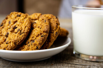 Close-up of cookies on a white plate and a glass of milk on a wooden background.