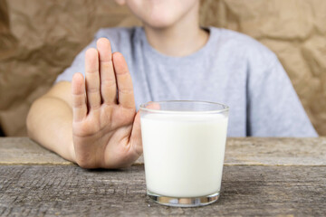 The boy looks at a glass of milk and shows a stop sign with his hand. A health problem related to...