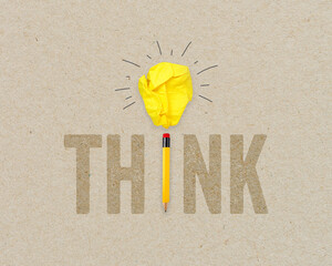 Yellow paper light bulb metaphor for idea with pencil on brown recycled background
