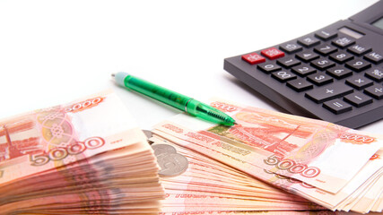 Coins with Russian banknotes, calculator and pen isolated on a white background, panoramic banner format, close-up, space for text