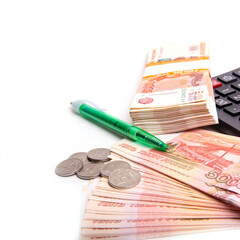 Coins with Russian banknotes, calculator and pen isolated on a white background, panoramic banner format, close-up, space for text
