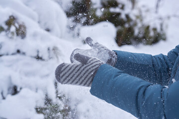 Woman in mittens claps hands in the snow.