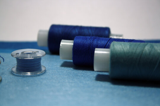 Blue sewing threads and spools on a blue felt background.