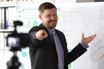 Male in suit and tie show stats graph pad making promo videoblog or photo in office camcorder to...