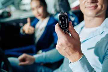 Happy customer showing electronic keys of car he just bought