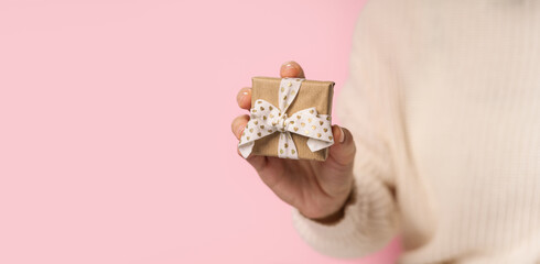 Beauty Woman hands holding Gift box with heart ribbon on pink background, close-up. pastel colors, copy space for text. Valentine gift. Banner for Christmas, hew year, birthday concept.