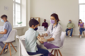 Careful nurse in a medical face mask giving a flu vaccine to her little patient