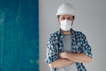 Portrait of pensive construction engineer with protective face mask and white hard hat