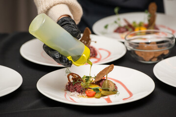 Chef pouring sauce on the Beef Tartare with Various Dip and Vegetables