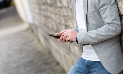 Man standing against a wall and using mobile phone