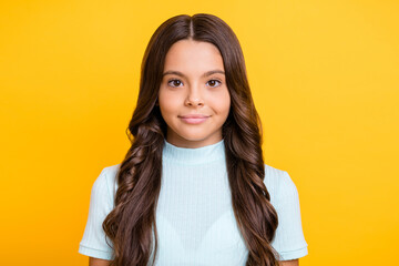 Photo portrait of calm small brunette girl smiling wearing blue casual clothes isolated on vivid yellow color background