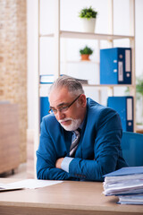 Old male bookkeeper unhappy with excessive work at workplace