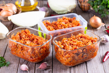 Stewed cabbage in a container on a wooden background for freezing. Frozen food,