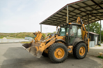 Yellow tractor on gas station. Refill. Heavy equipment. Tanks with fuel.