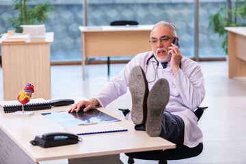 Old male doctor cardiologist working in the clinic