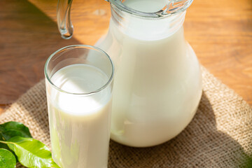 Glass pitcher of milk on old wooden table