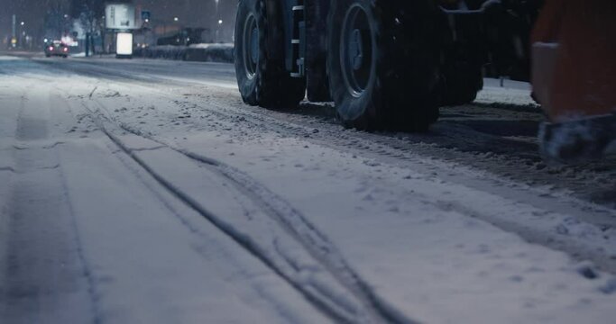 Snow plow tractor drive by snow on road winter night wheels close up