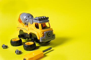 Construction machine concrete mixer made of plastic on a yellow background with a place for text...