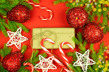 Christmas composition. Gifts, spruce branches, red shiny decorations and christmas tree toys on a red background
