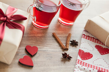 Festive table setting for Valentine's Day with plate, gift boxex, fork, knife and hearts on a wooden table. Love anniversary.