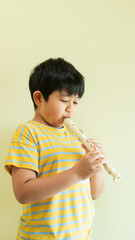 A young child is playing the flute. Art for kid. A little boy with a musical instrument. A music tuition lesson. Creative kid with the classical song education. © Natcharlai