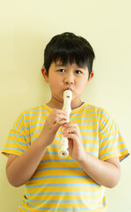 A young child is playing the flute. Art for kid. A little boy with a musical instrument. A music tuition lesson. Creative kid with the classical song education. © Natcharlai