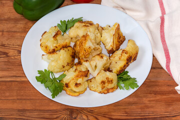 Cauliflower pieces fried in batter on dish on rustic table