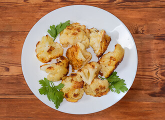 Cauliflower fried in batter on dish on table, top view