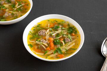 Homemade Sopa a La Minuta in white bowls on a black background, low angle view.