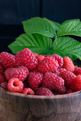 Raspberry. Fresh beautiful, red raspberries on a dark wood background. Green leaves. Place for text