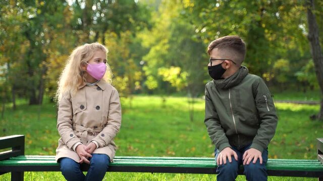 children wearing face mask outside in the Coronavirus COVID-19 pandemic, sitting on a chair outside, wearing a  mask, protecting his face from polluted airborne dust and wearing a mask 