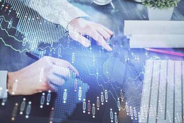 Double exposure of man's hands holding and using a phone and financial graph drawing. Analysis concept.