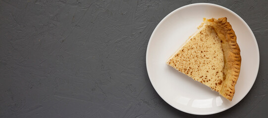 Piece of Homemade Sugar Cream Pie on a white plate on a gray background, top view. Flat lay, overhead, from above. Copy space.