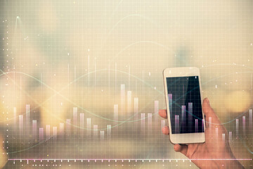 Double exposure of forex chart sketch hologram and woman holding and using a mobile device. Stock market concept.