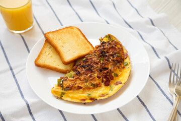 Homemade Denver Omelette on a white plate on cloth, low angle view.