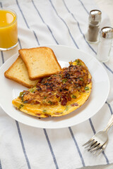 Homemade Denver Omelette on a white plate on cloth, side view.
