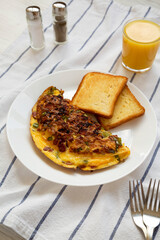Homemade Denver Omelette on a white plate on cloth, low angle view.
