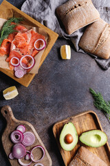 Top view of smoked salmon slices with onion, dill, lemon and avocado on a table with copy space.