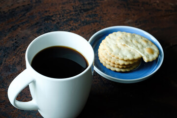 black hot coffee served with wheat crackers on dark wooden table