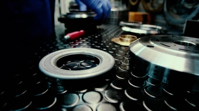 Close up view on car mechanic making new disks plates for the auto. Process of repairing car's parts. Working in the garage. Tools and details on the table.