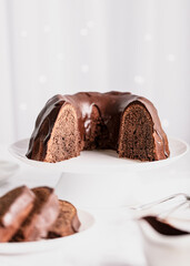 Dark chocolate cake covered with icing on a white stand. Selective focus.