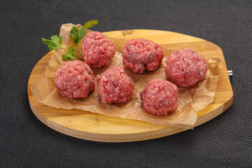 Raw meatball over wooden background